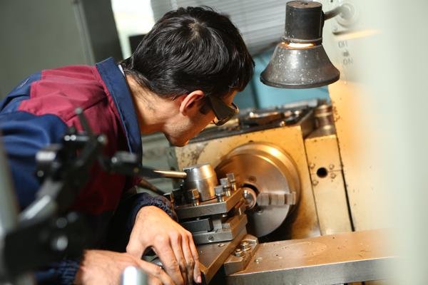 next_image: Worker at a lathe